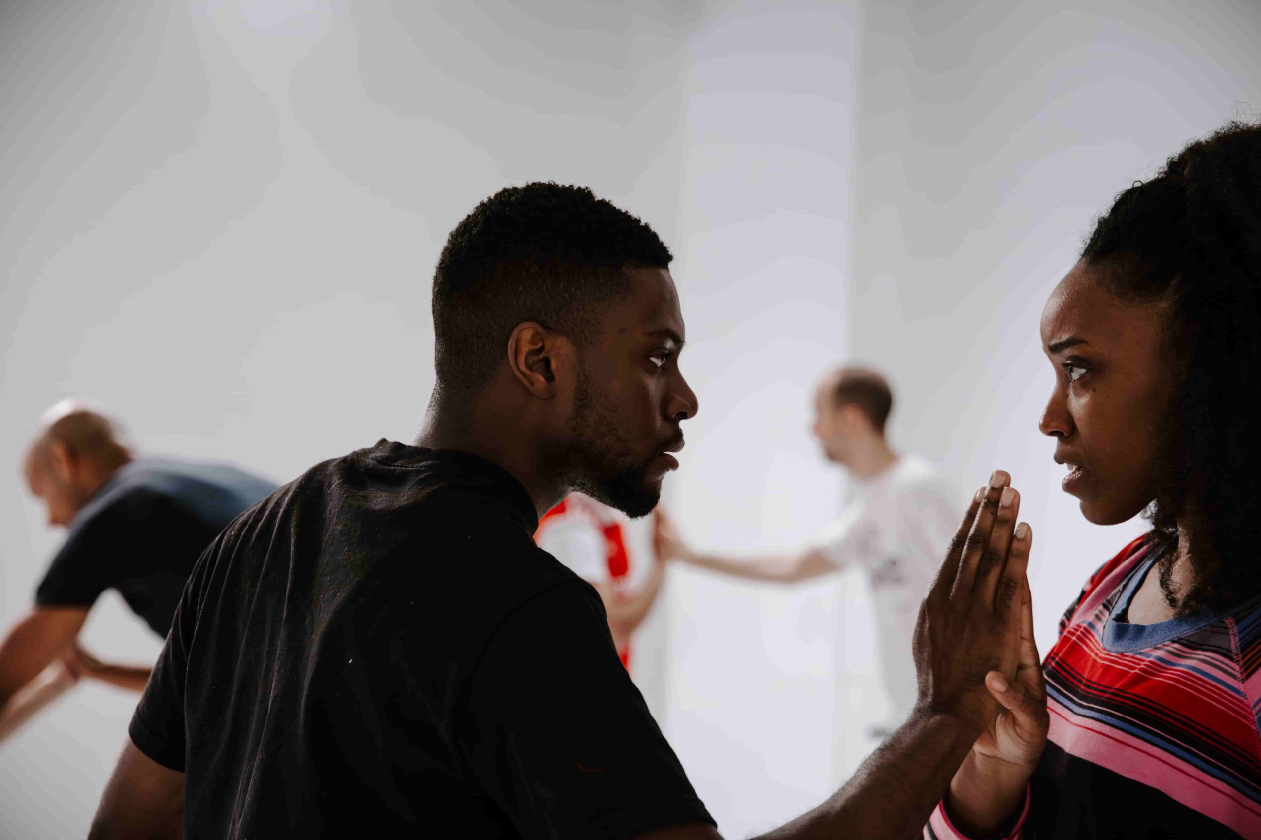 two actors looking intensely at each other in an acting class, palms touching